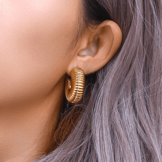 Gold hoop earring worn by a person with gray hair