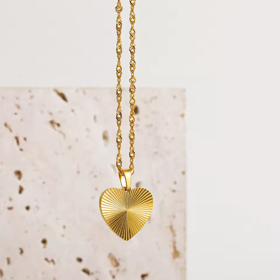 Gold heart-shaped pendant necklace on a textured surface