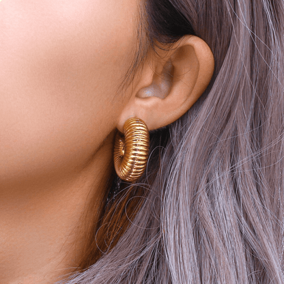 Gold hoop earring worn by a person with gray hair